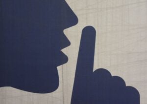 Silhouette illustration showing a person's profile with a finger raised to lips in a shushing gesture, representing quiet HVAC operation.