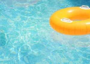 Bright yellow inflatable ring float on clear turquoise swimming pool water with rippled surface patterns.